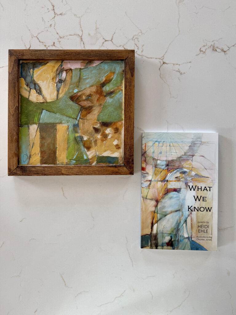 Abstract, colorful painting in a wooden frame leaning on a marble-surfaced wall, beside a booklet titled 'What We Know'.