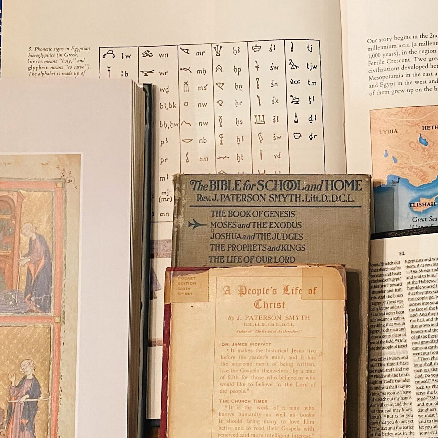 Open page showing a table of Egyptian hieroglyphs alongside a vintage 'Bible for School and Home' booklet and a small map excerpt in the corner.
