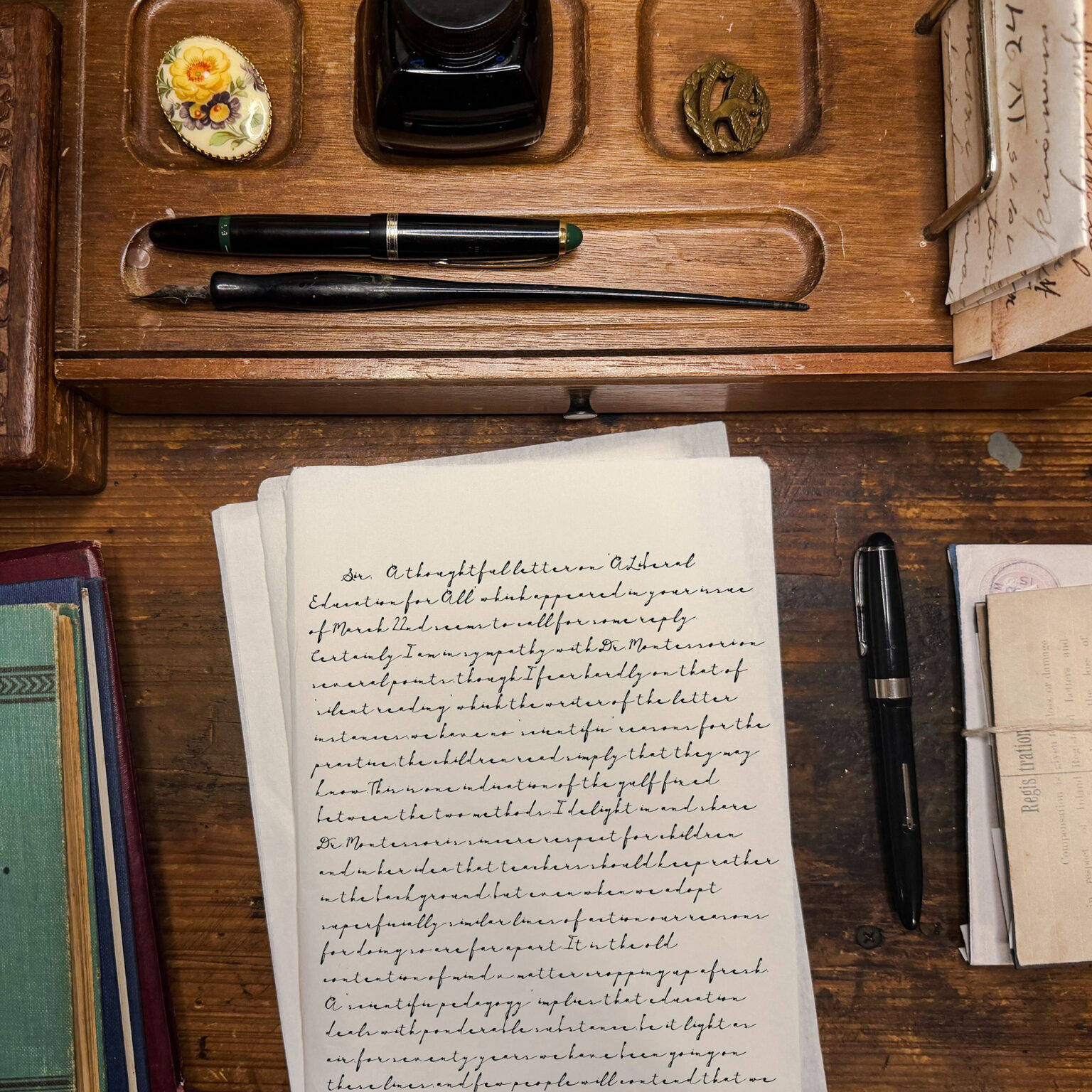 Vintage writing desk scene with a black fountain pen, a dip pen, ink bottle, and handwritten letters on a wooden surface.