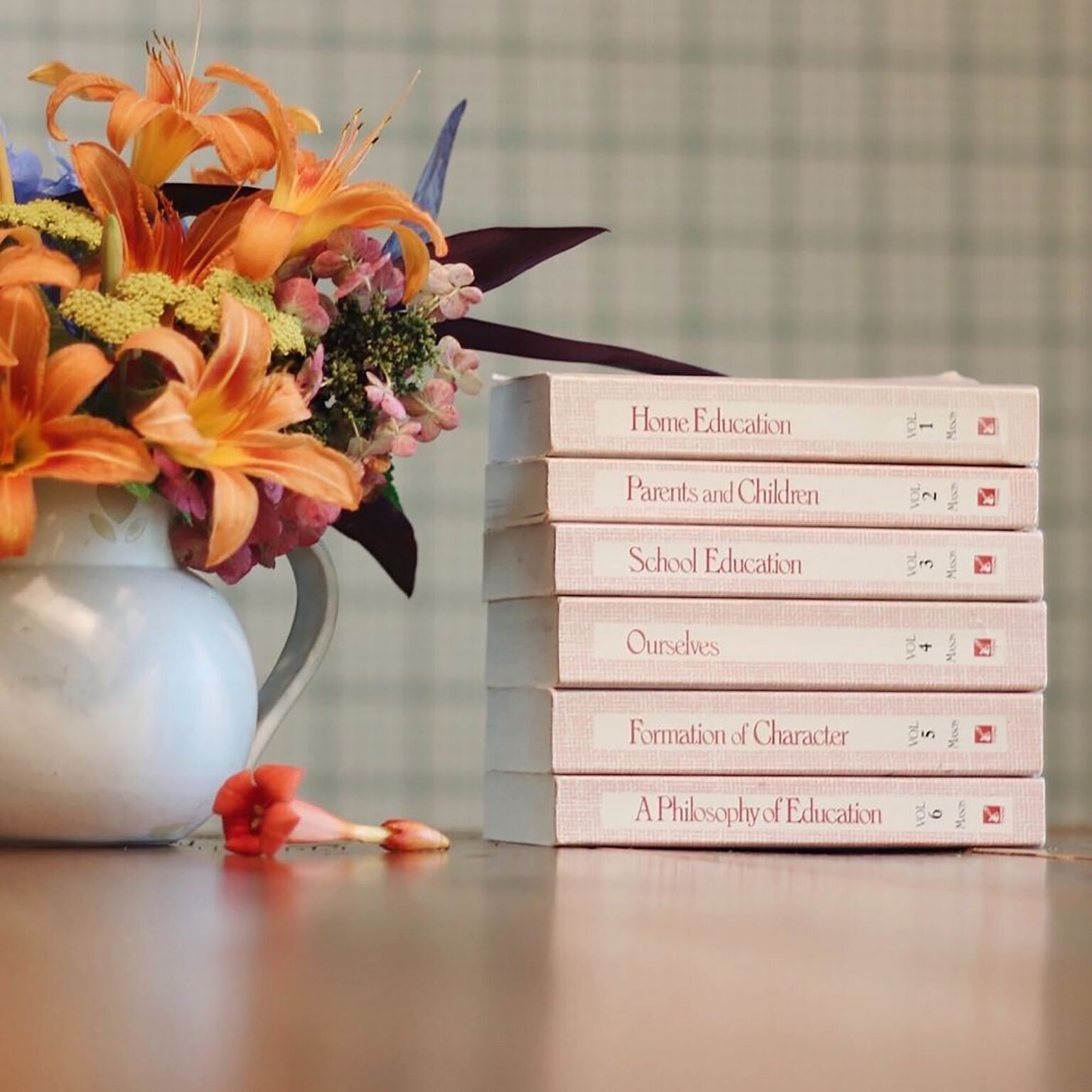 Vibrant orange bouquet beside a stack of education textbooks on a table.