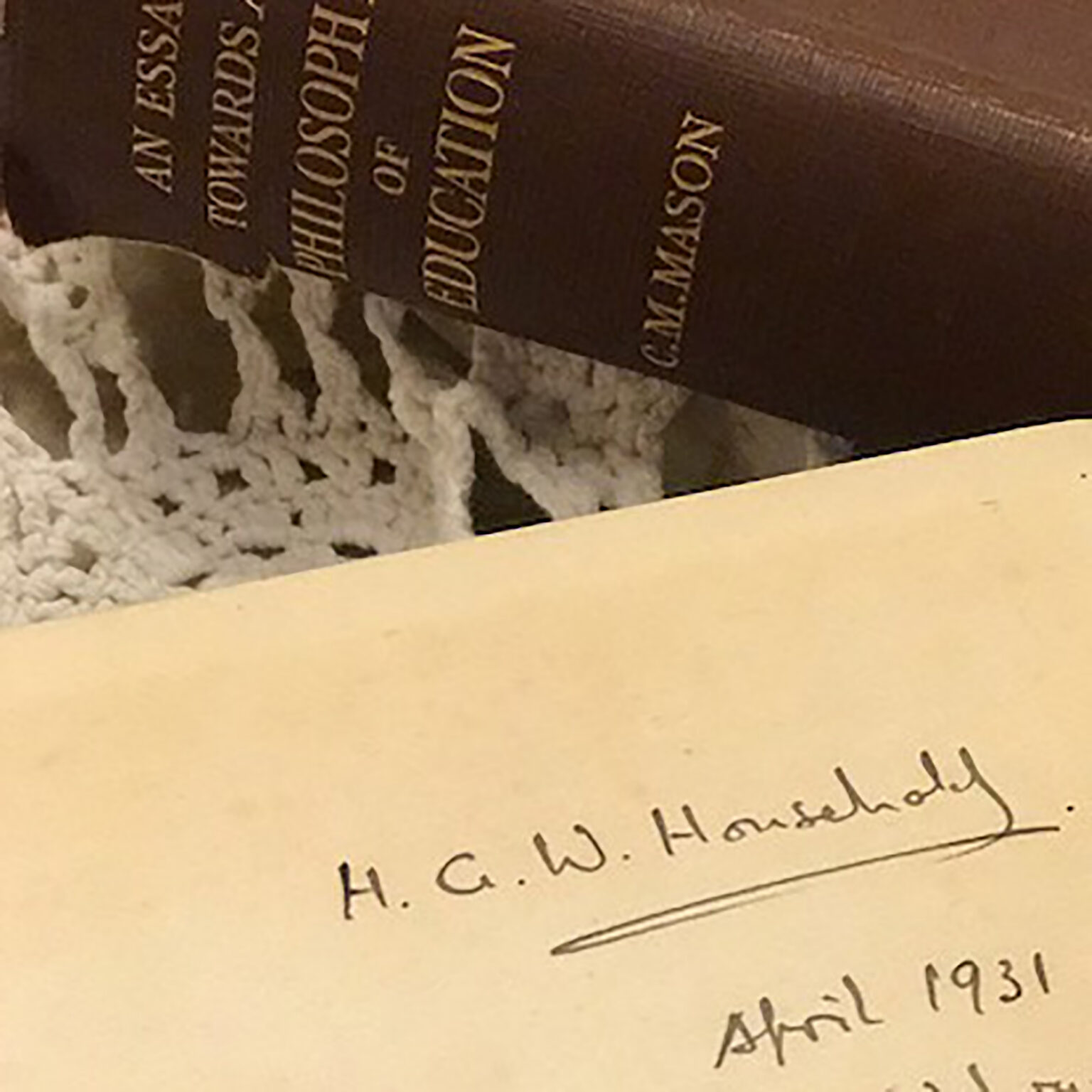 Close-up of a dark bookmark with gold vertical lettering (appears to say 'HOUSTON') resting on a page with cursive handwriting visible nearby.