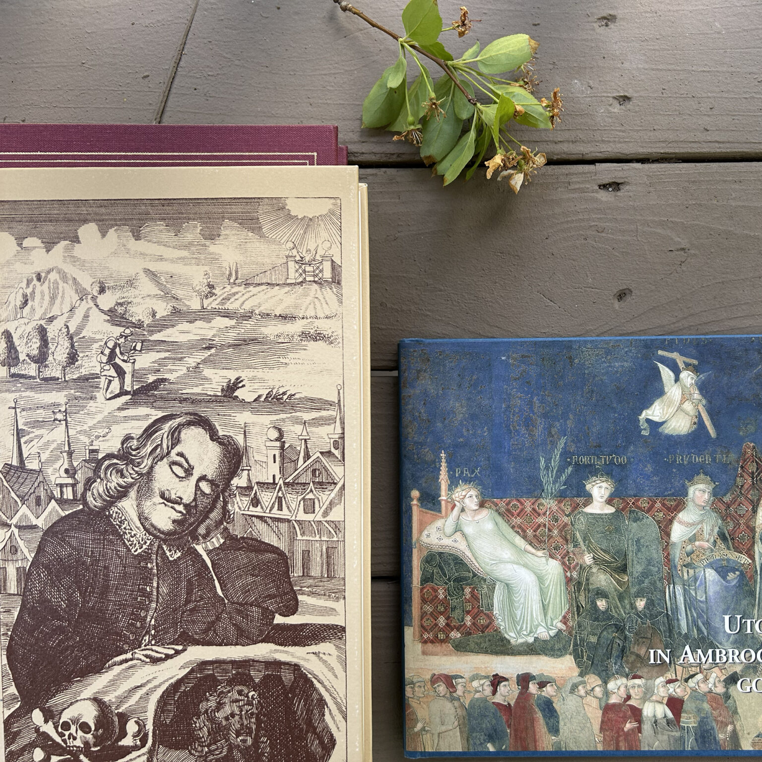 Old hardcover books stacked on a weathered wooden surface with a dried bouquet resting on top.