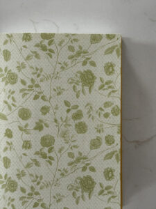 Close-up of a beige book cover with a green rose and vine pattern.