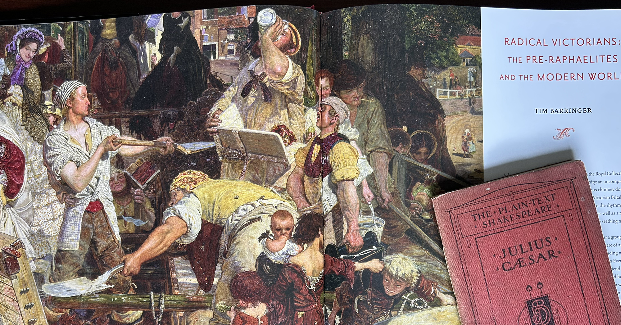 Busy Victorian marketplace scene inside a book: people in period clothing, some drinking, arguing, and watching a central figure; page title visible on the right.