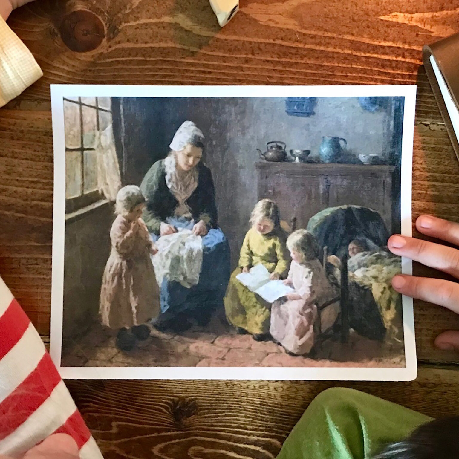 Framed print of a classical domestic scene: a mother and several children gathered around a table indoors.