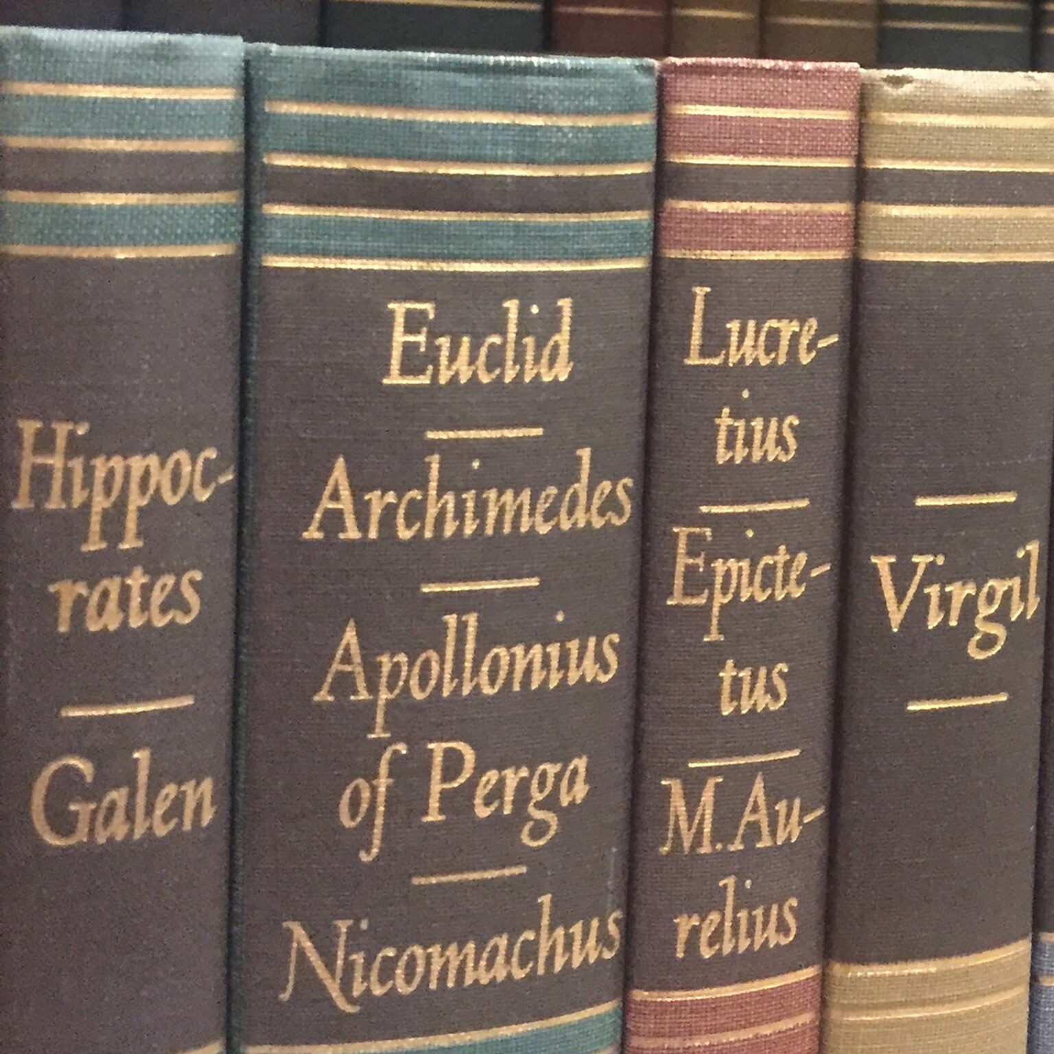 Close-up of vintage book spines with gold lettering, titles including Euclid and Archimedes.