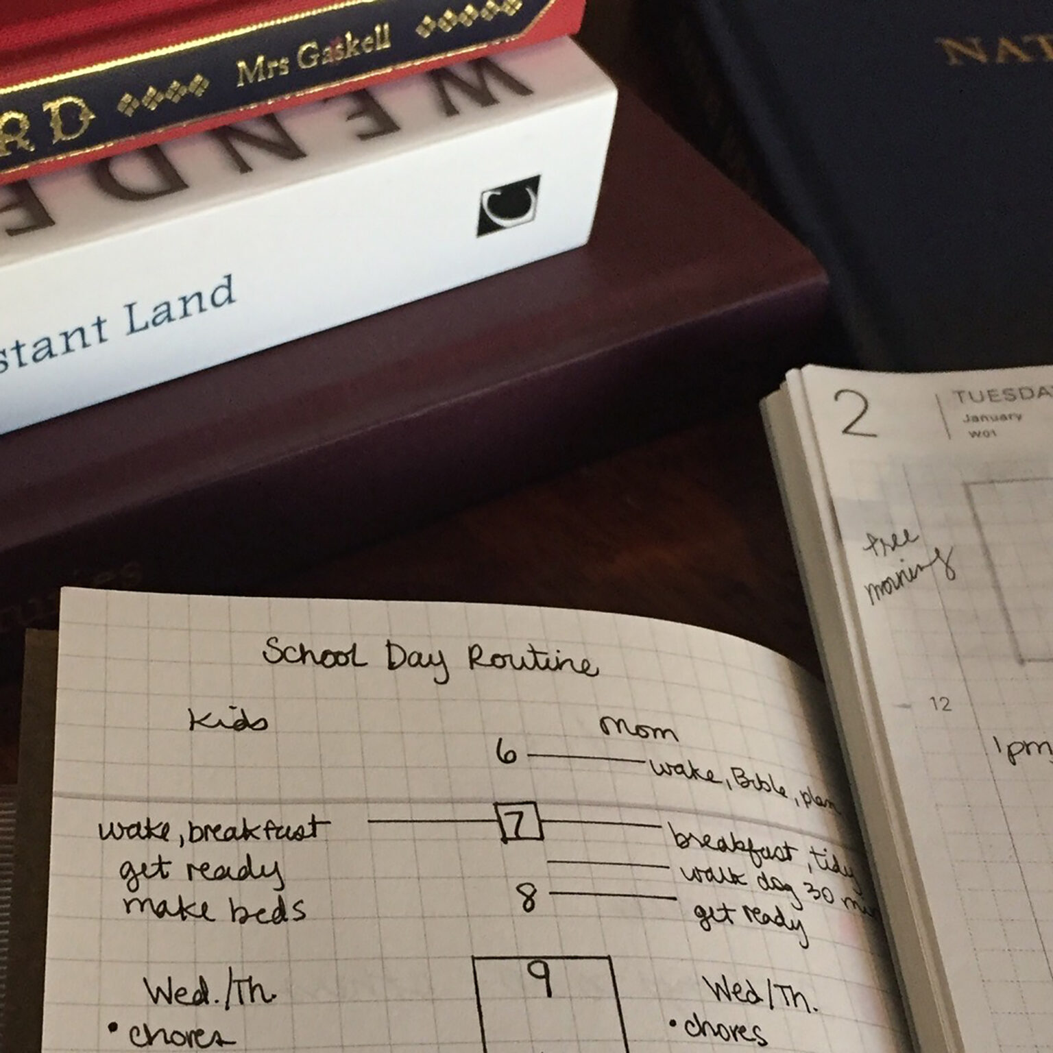Notebook page titled 'School Day Routine' with handwritten schedule and a weekly timeline, surrounded by books and a calendar.